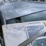 Voiture grélée : capot et pare-brise avec impacts et fissure